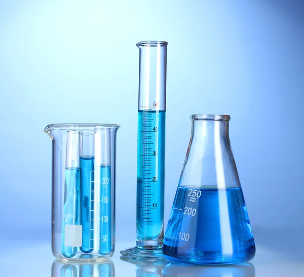 Φαρμακευτικός και εργαστηριακός εξοπλισμός με μπλε υγρό με αντανάκλαση σε μπλε φόντο — Φωτογραφία Αρχείου