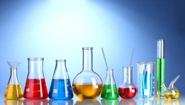 Diferentes cristalería de laboratorio con líquido de color y con reflexión sobre blu —  Fotos de Stock