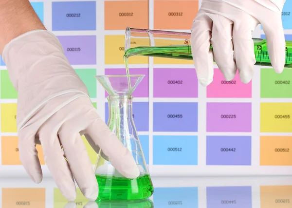 Laboratory flask and tube with green liquid in scientist's hands on co — Stock Photo, Image
