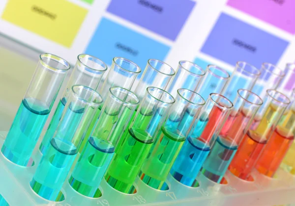Tubes à essai avec liquide de couleur sur fond d'échantillons de couleur — Photo