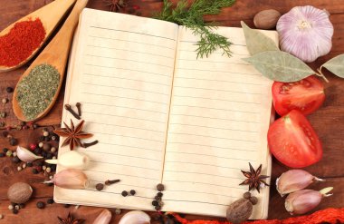 Notebook for recipes and spices on wooden table clipart