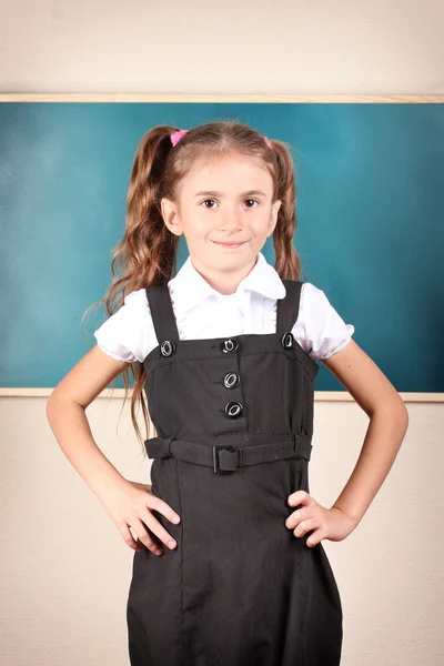 Mooi meisje permanent in de buurt van schoolbord in het klaslokaal — Stockfoto