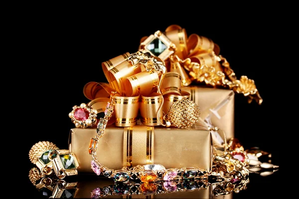 Various gold jewellery and gifts on black background — Stock Photo, Image