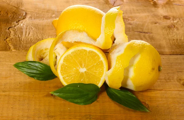 Спелые лимоны с листьями на деревянном столе — стоковое фото