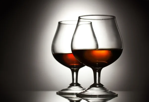 Dwie szklanki koniaku na szarym tle — Zdjęcie stockowe