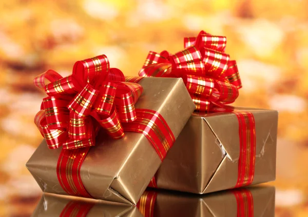 Schöne goldene Geschenke mit roter Schleife auf gelbem Hintergrund — Stockfoto