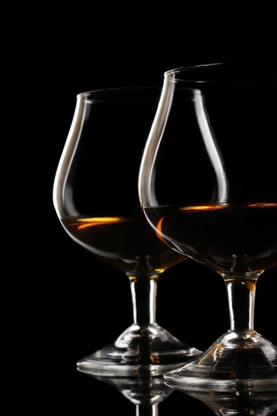 Dwie szklanki koniaku na czarnym tle — Zdjęcie stockowe