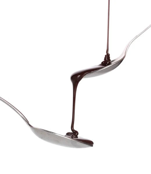 Cioccolato versato in un cucchiaio e da esso ad un altro cucchiaio isolato su whit — Foto Stock