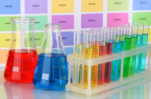 Test tüpleri ve renk örnekleri arka plan üzerinde renkli sıvı şişe — Stok fotoğraf