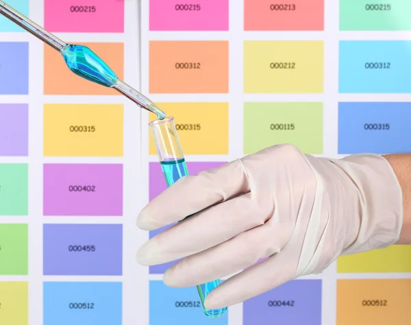 Reageerbuis met blauwe vloeistof en Pipetteer in wetenschapper handen op kleur s — Stockfoto