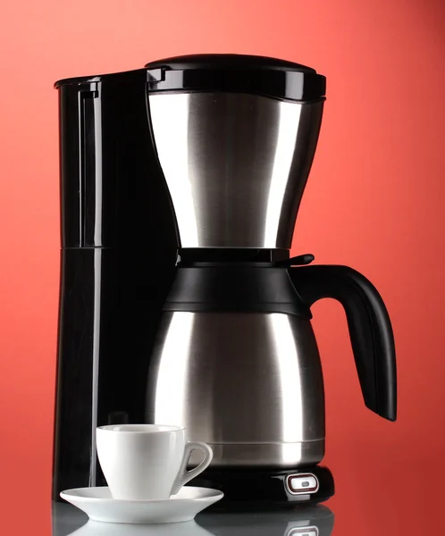 Кофеварка с белой чашкой на красном фоне — стоковое фото