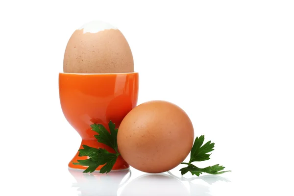 Vařená vejce v oranžové stojan a petržel izolovaných na bílém — Stock fotografie