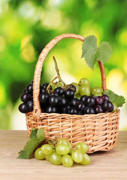 Ripe grapes in basket on green background — Stock Photo, Image