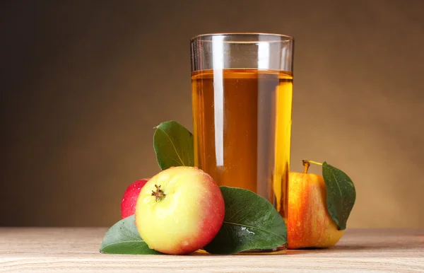 Succo di mela e mele su tavolo di legno su sfondo marrone — Foto Stock