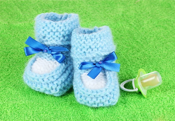 Azul baby booties e chupeta no fundo verde — Fotografia de Stock