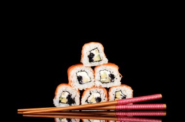 Tasty rolls with chopsticks isolated on black clipart