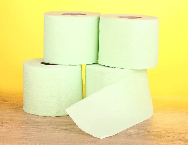 Groene rollen wc-papier op houten tafel op gele achtergrond — Stockfoto