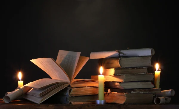 Stapel van oude boeken met kaars en Blader in donker — Stockfoto