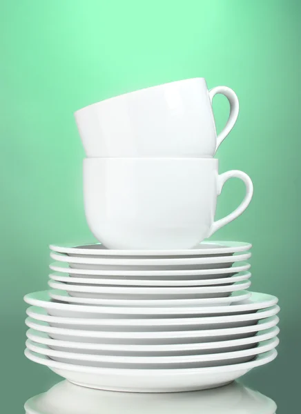 Чистые тарелки и чашки на зеленом фоне — стоковое фото