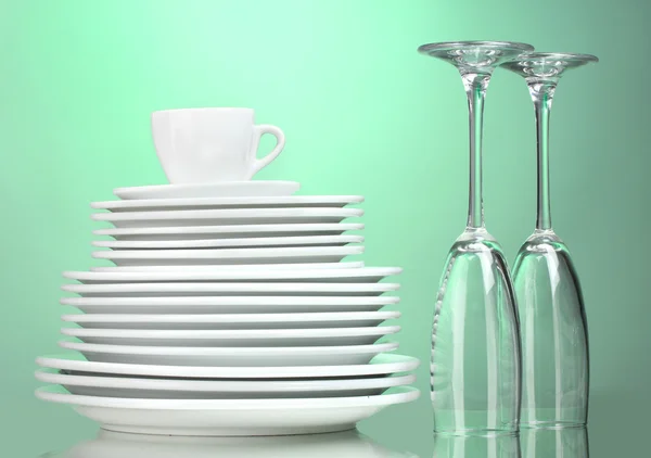 Assiettes propres, tasse et verres sur fond vert — Photo
