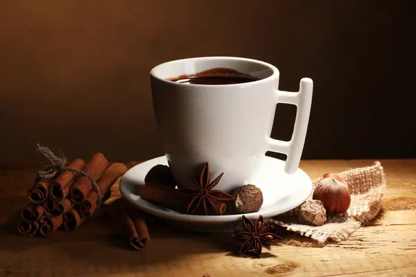 Tazza di cioccolata calda, bastoncini di cannella, noci e cioccolato sul tavolo di legno o — Foto Stock