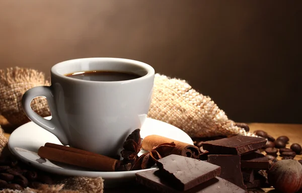 Xícara de café e feijão, paus de canela, nozes e chocolate na mesa de madeira o — Fotografia de Stock
