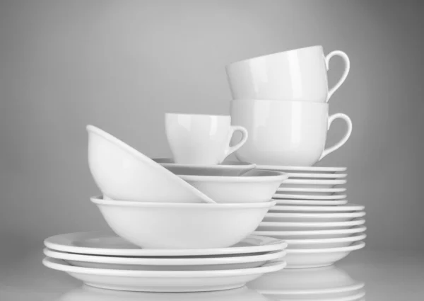 Ciotole vuote, piatti e tazze su sfondo grigio — Foto Stock
