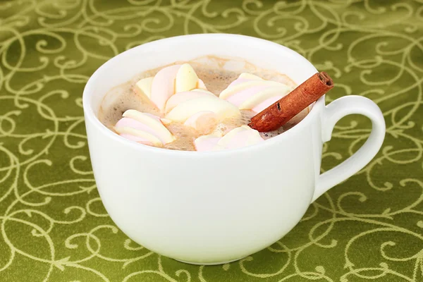 Xícara de cappucino com marshmallows e canela na toalha de mesa verde — Fotografia de Stock