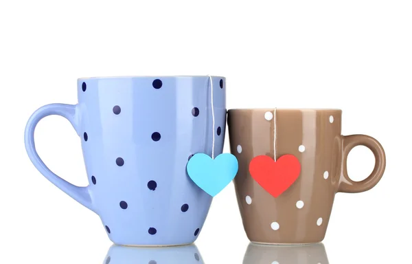 Iki bardak ve etiketli whit üzerinde izole kırmızı ve mavi kalp şeklinde çay poşetleri — Stok fotoğraf