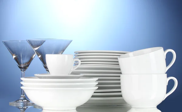 Ciotole vuote, piatti, tazze e bicchieri su sfondo blu — Foto Stock