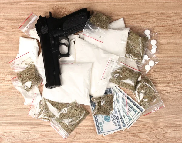 可卡因和大麻在软件包、 美元和木制背景上的手枪 — 图库照片
