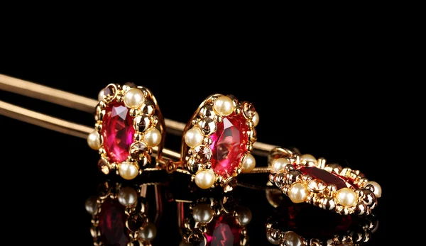 Schöne goldene Ohrringe und Halskette mit Rubinen und Perlen auf schwarzem Backgr — Stockfoto