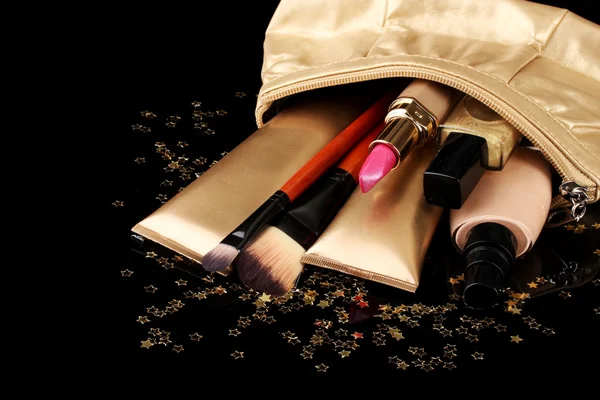 Bolsa de maquiagem dourada bonita e cosméticos isolados em preto — Fotografia de Stock