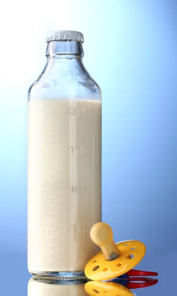 Üveg tejet és a cumit a kék háttér — Stock Fotó