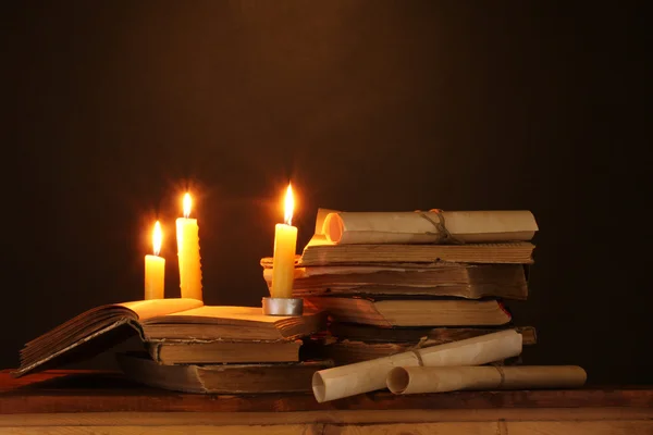 Pile de vieux livres avec bougie et rouleau dans l'obscurité — Photo