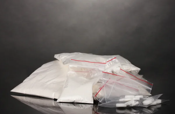 Cocaína e drogas em embalagens de fundo cinzento — Fotografia de Stock