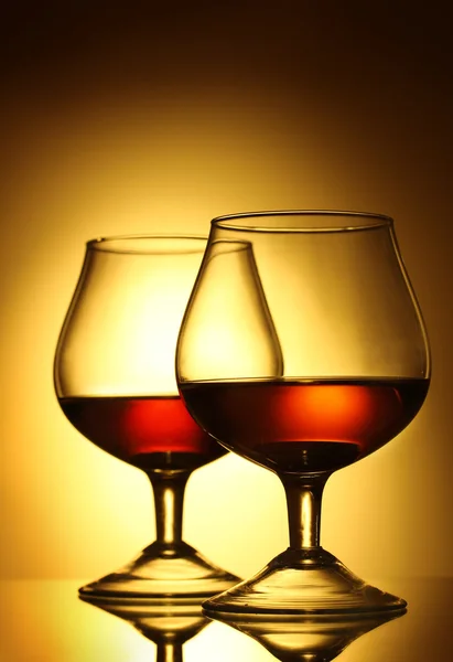 Two glasses of cognac on yellow background — Stock Photo, Image