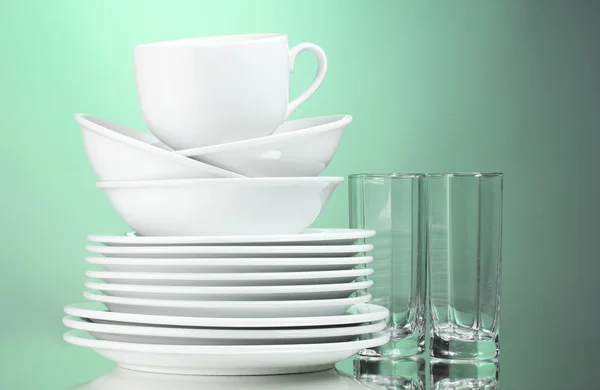 Platos limpios, taza y vasos sobre fondo verde —  Fotos de Stock