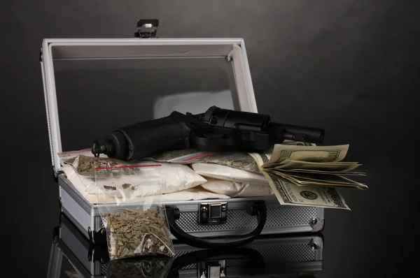 コカインおよびマリファナを灰色の背景上のスーツケースで銃を持つ — ストック写真