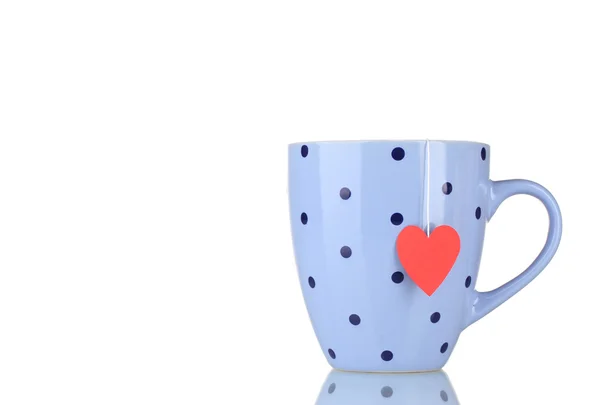 Blå kopp och tepåse med röda hjärtformade etikett isolerad på vit — Stockfoto