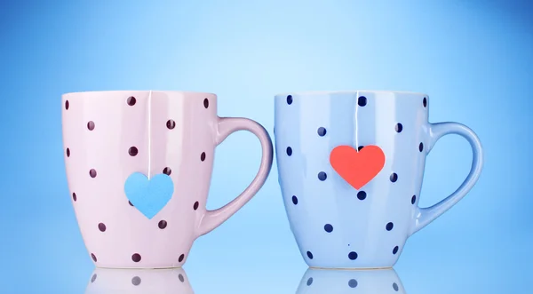 Deux tasses et sachets de thé avec étiquette rouge et bleue en forme de coeur sur fond bleu — Photo