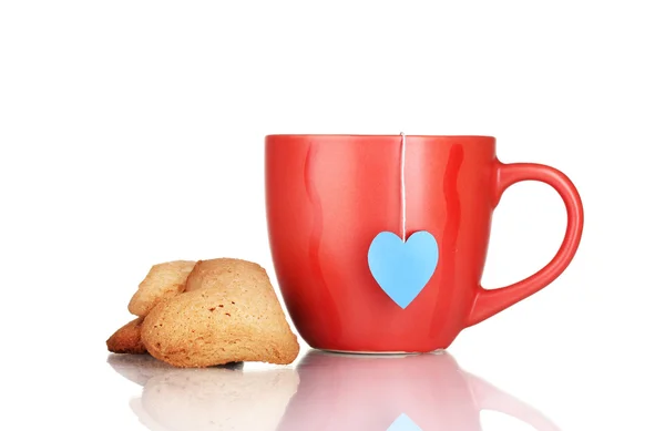 Taza roja con bolsa de té y galletas en forma de corazón aisladas en blanco —  Fotos de Stock
