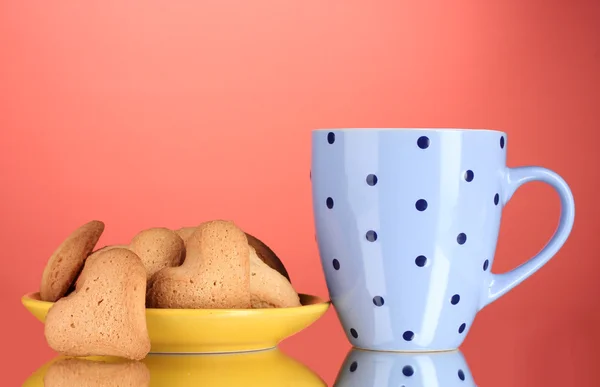 Sarı tabak ve bardak kırmızı zemin üzerinde kalp şeklinde kurabiye — Stok fotoğraf