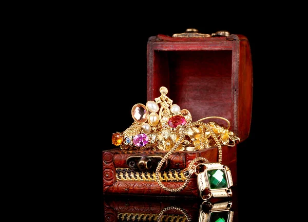 Cofre de madera lleno de joyas de oro sobre fondo negro — Foto de Stock