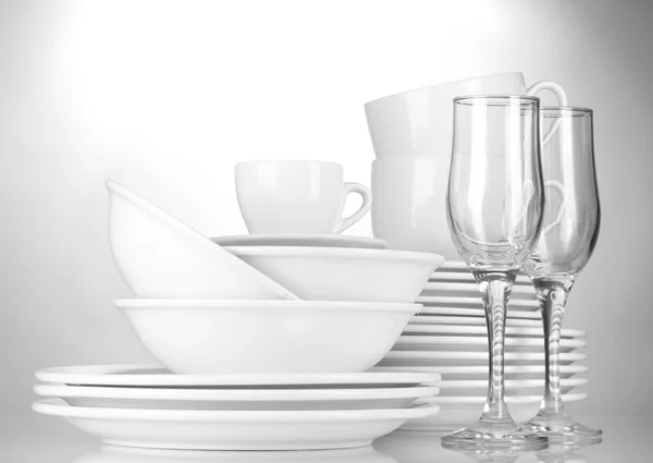 Tigelas vazias, pratos, copos e copos sobre fundo cinza — Fotografia de Stock