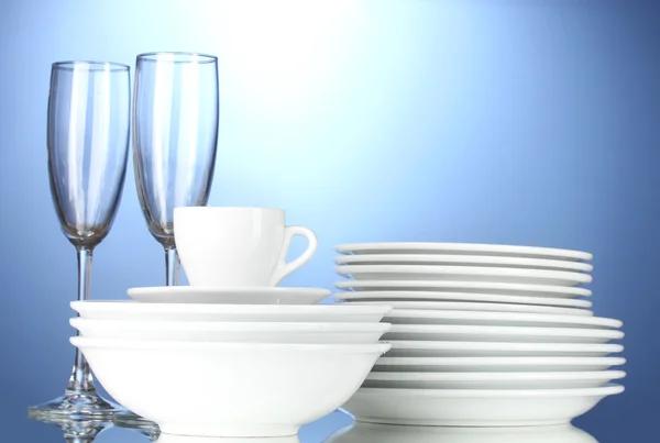 Cuencos vacíos, platos, tazas y vasos sobre fondo azul —  Fotos de Stock