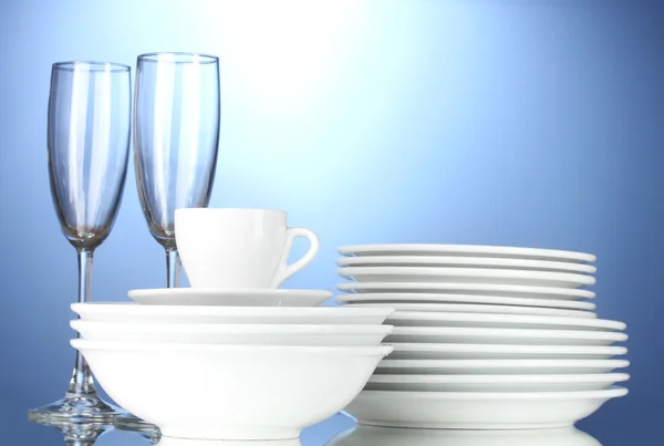 Empty bowls, plates, cups and glasses on blue background — Stock Photo, Image