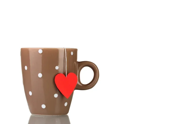 Коричневая чашка и пакетик чая с красной этикеткой в форме сердца, изолированной на белом — стоковое фото