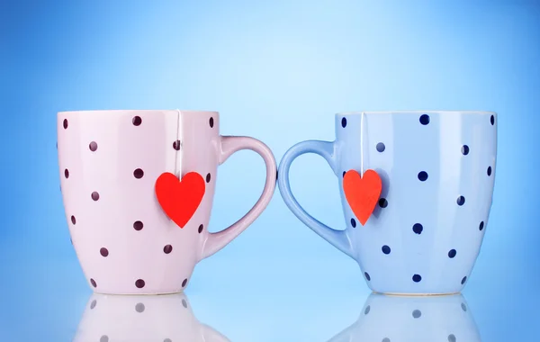 Duas xícaras e sacos de chá com rótulo vermelho em forma de coração no fundo azul — Fotografia de Stock