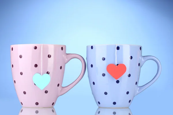 Iki bardak ve çay poşetleri kırmızı ve mavi kalp şeklinde etiketi — Stok fotoğraf